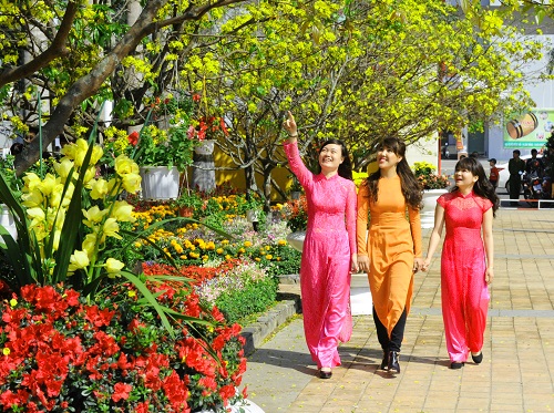 Charming girls in ao dai walking through the Spring Flower Garden at the 29 March Park