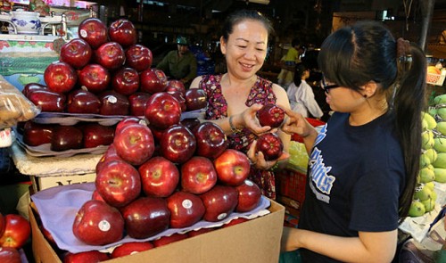 A woman (R) is seen buying imported fruit at a shop in Ho Chi Minh City.