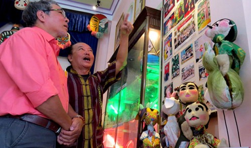 Mr Hoc (in red shirt) is seen introducing his puppets to a visitor