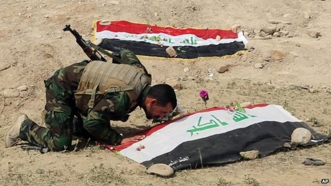 Một người lính Iraq tỏ lòng thành kính trước thi thể đồng đội bị IS giết. Ảnh: AP
