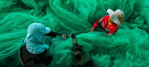 The winning photo by photographer Pham Ty which captures the scene of two women weaving a giant fish net at a small village. (Source: anyarena.com)