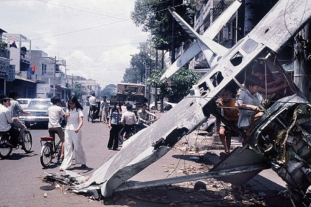 Xác một chiếc trực thăng cỡ nhỏ của không quân Việt Nam Cộng hòa rơi trên đường Nguyễn Hoàng ngày 29/4, giờ đây còn lại là một đống đổ nát, thu hút sự tò mò, hiếu kỳ của những em nhỏ. (Ảnh: Herve Gloaguen/Gamma-Rapho)