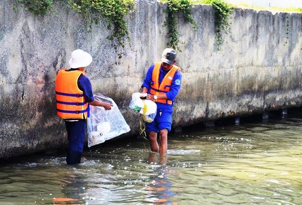 Công nhân Xí nghiệp Dịch vụ môi trường số 1 vớt những rác thải còn sót lại trên sông Hàn, phía trước khán đài.