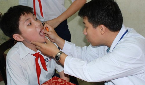 A young doctor checks the mouth of a child during the national voluntary campaign