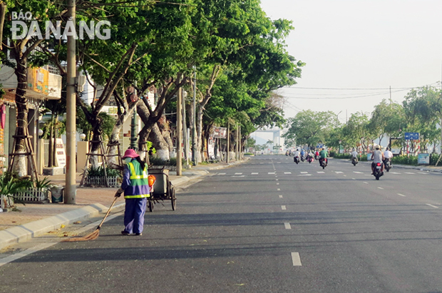 Công việc của chị lao công sẽ bớt vất vả hơn nếu không có đám tang đi qua con đường này. 