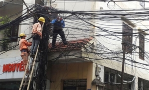 Viet Nam Electricity (EVN) workers checkpower lines at a street corner 