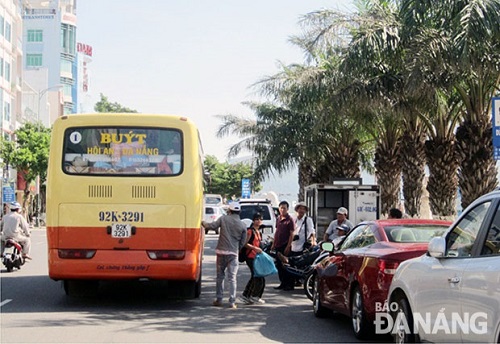 A bus picking up/dropping off passengers in the road due to illegal parking of cars 