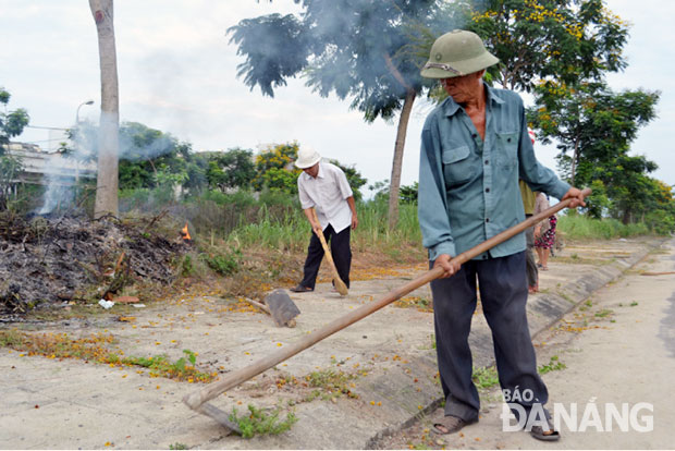 Ông Phan Minh Nhuận (phải) làm vệ sinh môi trường tại khu dân cư.