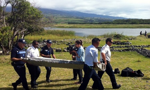 Cảnh sát vận chuyển mảnh vỡ nghi là của máy bay MH370 tìm thấy trên đảo Reunion, Pháp. Ảnh: Reuters