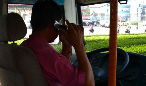 A man is seen using a cellphone while driving a bus in Bien Hoa City, Dong Nai Province