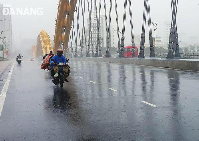 Gió mạnh, mưa to khiến người dân đi xe máy lưu thông qua cầu rất khó khăn