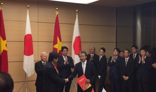 General Secretary of the Communist Party of Vietnam Nguyen Phu Trong (left, back) and Japan's Prime Minister Shinzo Abe witness the signing of the MoU in Tokyo on September 15, 2015. Vietjet