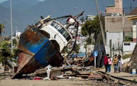 Sóng thần do động đất gây ra cuốn trôi một con tàu lên bờ. Ảnh AFP