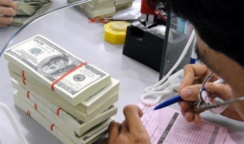 A bank employee works next to stacks of U.S. dollar notes in this file photo taken in Ho Chi Minh City. Tuoi Tre