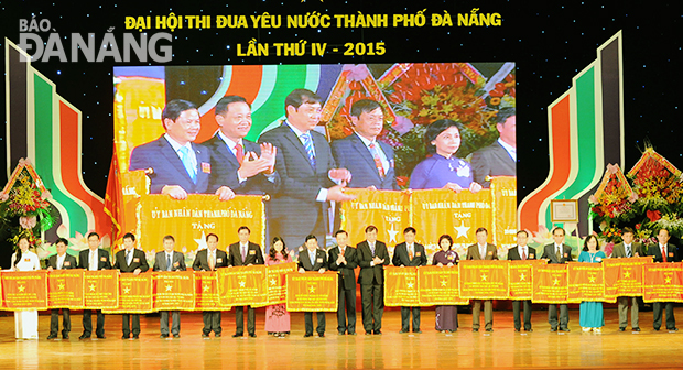 Bí thư Thành ủy, Chủ tịch HĐND thành phố Trần Thọ và Chủ tịch UBND thành phố Huỳnh Đức Thơ trao Cờ thi đua cho các tập thể tại đại hội. 			   	   Ảnh: ĐẶNG NỞ