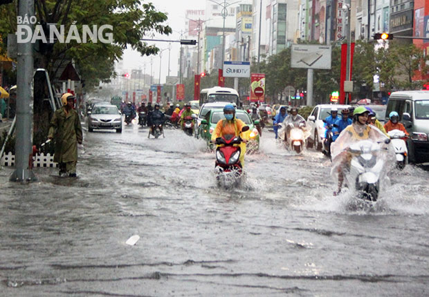 Lực lượng cảnh sát giao thông đứng làm cọc tiêu và hướng dẫn các phương tiện giao thông qua các khu vực ngập nước ở đường Nguyễn Văn Linh và Hàm Nghi.