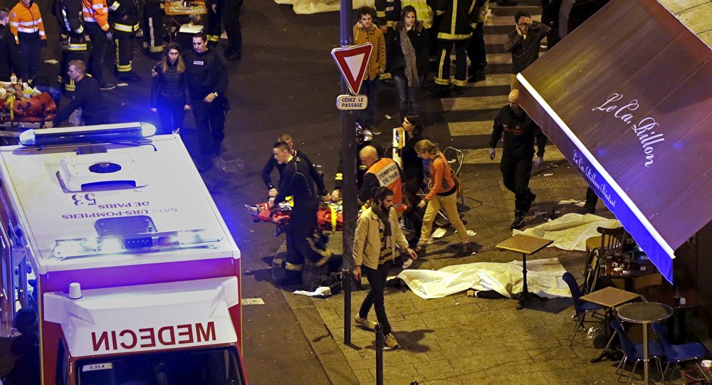Các nhân viên an ninh và cứu hộ đang hỗ trợ những nạn nhân bị thương trong vụ xả súng tại Paris hôm 13-11-2015. Ảnh: Reuters