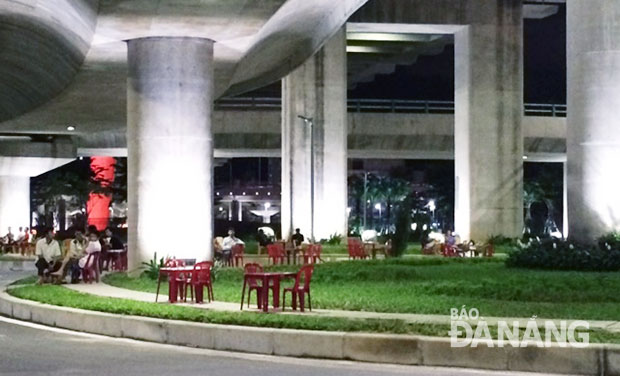 Buổi tối, các quán giải khát trên đường Tôn Đức Thắng bày bàn ghế ra khu vực gầm cầu cho khách ngồi, xe máy để ngay dưới lòng đường.