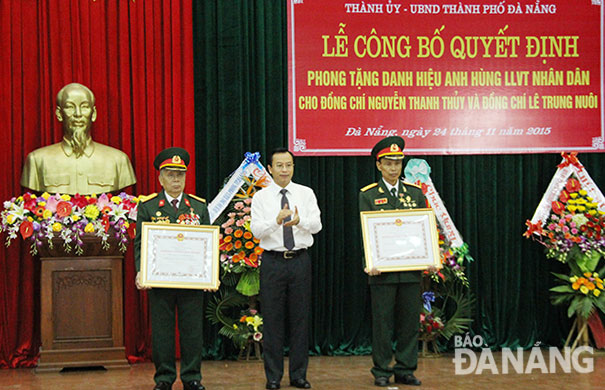 Thừa ủy quyền của Chủ tịch nước, Bí thư Thành ủy Đà Nẵng Nguyễn Xuân Anh trao danh hiệu Anh hùng Lực lượng vũ trang nhân dân cho hai đồng chí: Nguyễn Thanh Thủy (trái) và Lê Trung Nuôi. 									                     ảnh: ĐẮC MẠNH