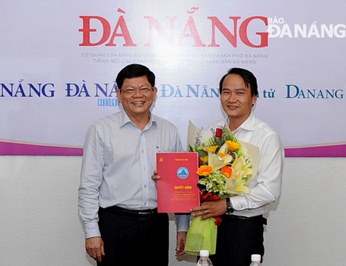 Deputy Secretary Tri presenting flowers to Editor-in-Chief Vinh (right)