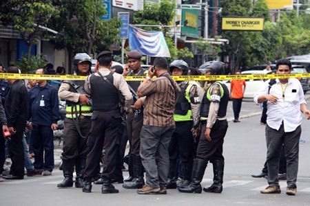 Indonesian police take position behind a vehicle as they pursue suspects after a series of blasts hit the Indonesia capital Jakarta on January 14.