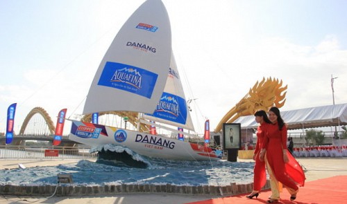 Women walk past a mock-up yacht on display to embrace the Clipper Round the World in Da Nang 