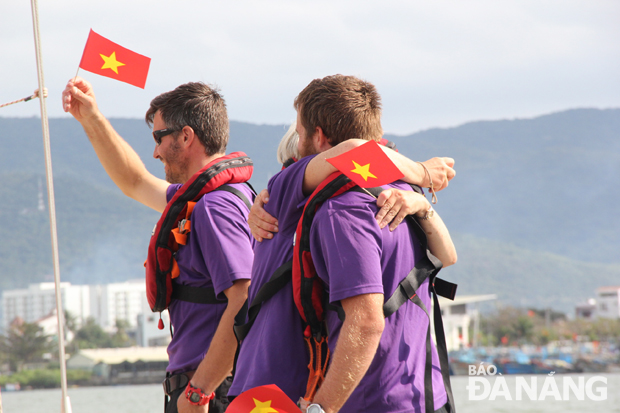 Các thành viên của thuyền đua vẫy chào người dân Đà Nẵng với lá quốc kỳ Việt Nam