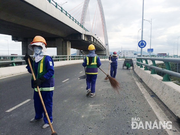 Các nhân viên Công ty CP Môi trường đô thị Đà Nẵng thu gom đá rơi vãi. (Ảnh chụp lúc 8 giờ 30 ngày 17-2) 