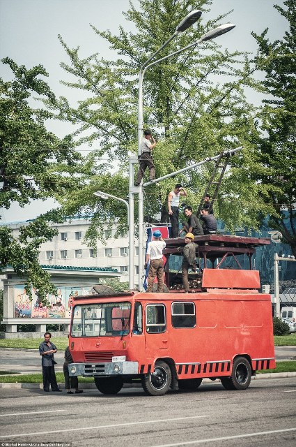 Những người công nhân đứng trên chiếc xe cũ kỹ để sửa điện