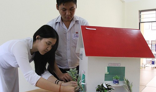 Tran My Duyen (L) and Quach Duc Huy are pictured making small changes to their house model. Tuoi Tre