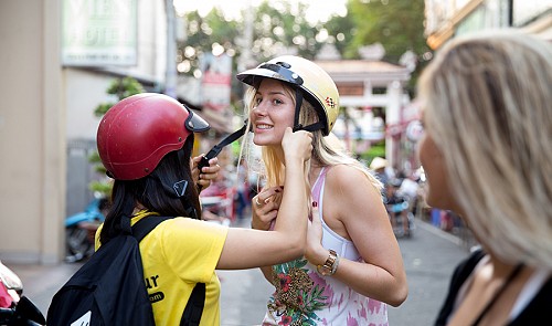 A Vietnamese volunteeer helps a U.S. tourist wear a helmet before taking a tour around Ho Chi Minh City. Tuoi Tr