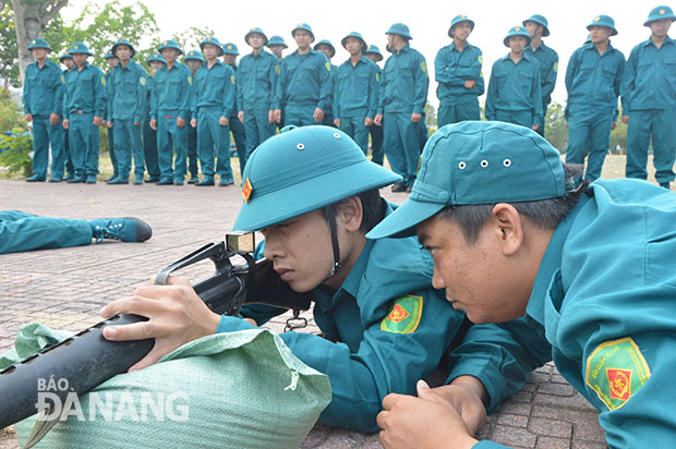 Anh Bùi Văn Quang (bên phải), Chỉ huy phó Ban Chỉ huy Quân sự phường Hòa Thọ Tây (quận Cẩm Lệ), hướng dẫn chiến sĩ dân quân ngắm bắn súng AR-15.