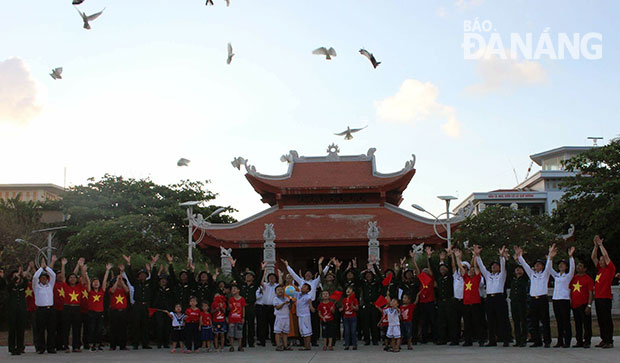 Các thành viên đoàn công tác vẫy chào những chú chim bồ câu được thả trên bầu trời ở đảo Trường Sa.		               Ảnh: NGỌC ĐOAN