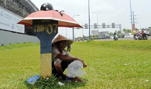 A man shelters himself under an umbrella to counter the hot spell along Hanoi Highway in Ho Chi Minh City. Tuoi Tre