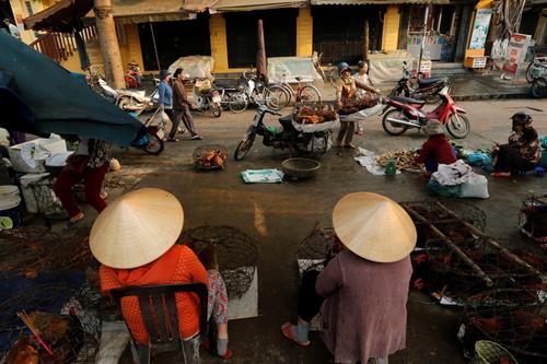  Women wearing traditional hats, known as a non la, sit in a market in Hoi An, Vietnam April 7, 2016. Photo: Reuters