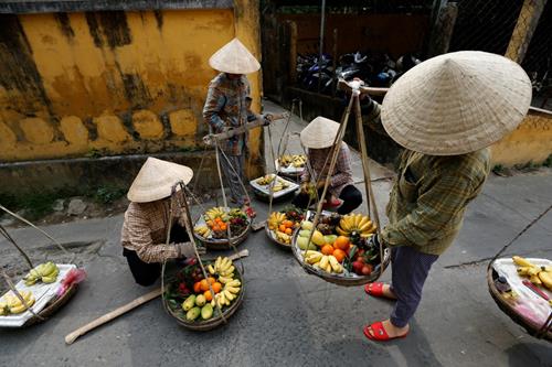 Women wearing traditional hats, known as non la, sell fruits in Hoi An, Vietnam April 4, 2016. Photo: Reuters