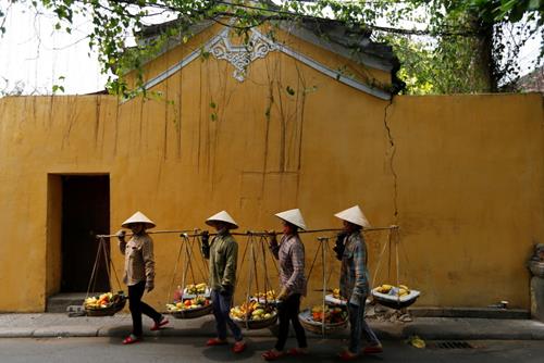 Women wearing traditional hats, known as non la, sell fruits in Hoi An, Vietnam April 4, 2016. Photo: Reuters