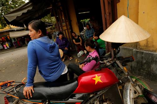 A woman sits on a motorcycle outside a market in Hoi An, Vietnam April 4, 2016. Photo: Reuters