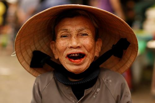 A woman wearing a traditional hat, known as a non la, poses for a portrait at a market in Hoi An, Vietnam April 5, 2016. Photo: Reuters