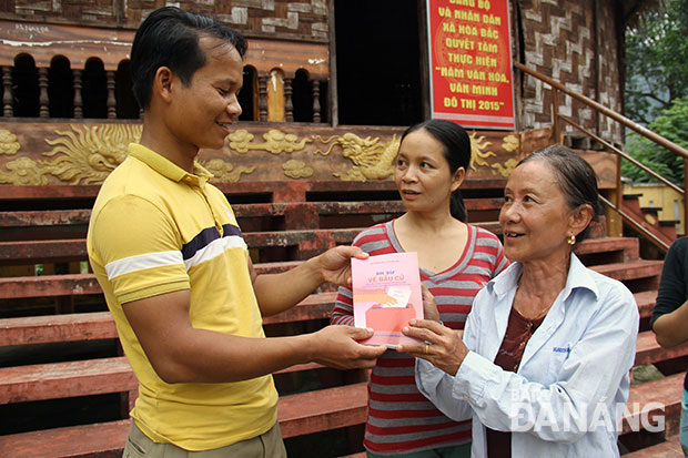 Anh Đinh Văn Cư (trái), Trưởng thôn Tà Lang (xã Hòa Bắc), trao tài liệu hỏi-đáp về bầu cử cho bà con dân tộc Cơtu.