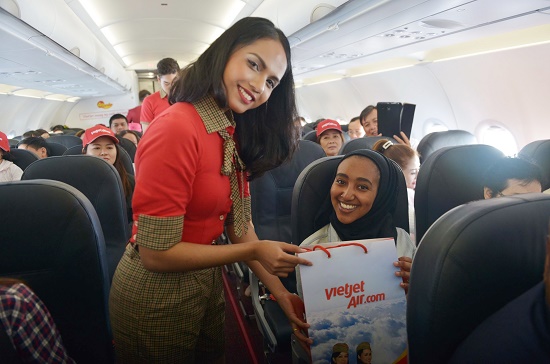 A passenger is seen posing for a photograph with a Vietjet flight attendant while receiving gifts from the carrier. Photo: Vietjet