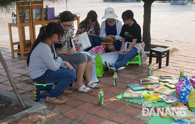 Châu Duyên (thứ 2 từ trái sang) đang đọc sách cho các em nhỏ trong một hoạt động thư viện sách tại Công viên Biển Đông. Ảnh: Nhật Hạ