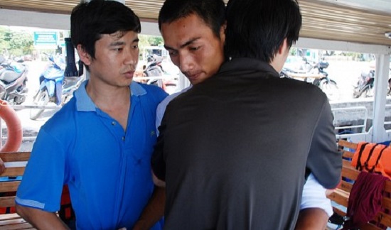 Luu Chi Dung (L) and Nguyen Duc Tai (R) embrace and thank Mai Van Dung for saving them and their family members.