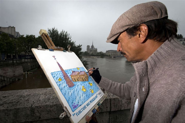 Nghệ sĩ người Pháp David Manuel Garcia, bên cầu sông Seine, vẽ nhà thờ Notre Dame de Paris trong nước lũ. 