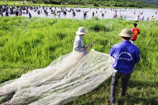 Three people are seen carrying their fishing nets to the swamp. Photo: Tuoi Tre