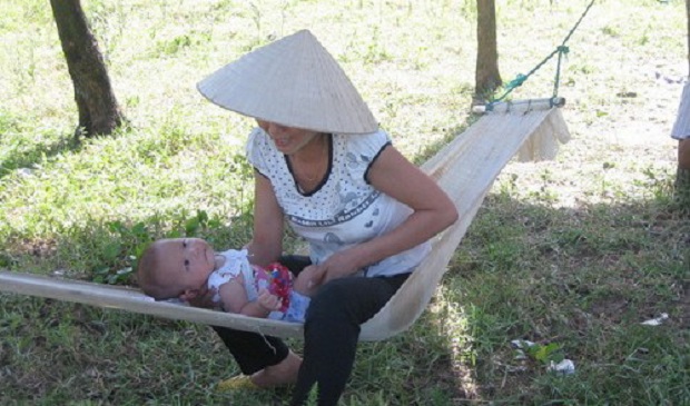 This file photo shows a mother soothing her baby under the shade of trees in a central province during scorching weather in 2014.Tuoi Tre