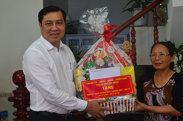 Chairman Tho (left) presenting a gift to a relative of war invalid Sang 