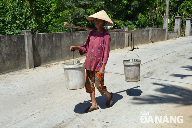  Bà Võ Thị Diệt vất vả đi lấy nước lúc trưa nắng. 