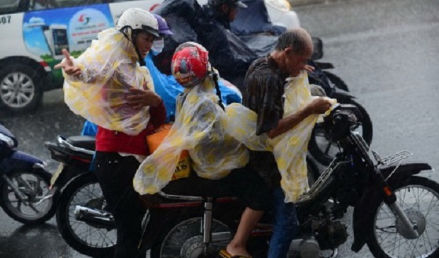 People are seen putting on raincoats during a torrential rain in Ho Chi Minh City. Tuoi Tre