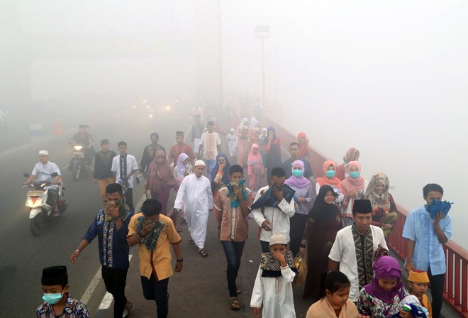 People cover their mouths and noses from the haze from wildfires (Photo: AP) 